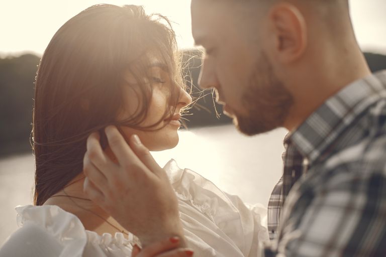 Close-up of a couple sharing an intimate moment outdoors at sunset.